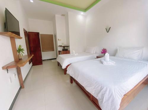 a bedroom with two beds and a tv in it at Tuong Vy Boutique Hotel Mui Ne in Mui Ne