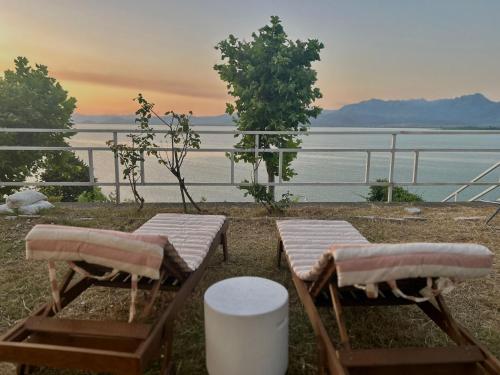 two chairs and tables with a view of the water at Pelikan Lake House in Shkodër
