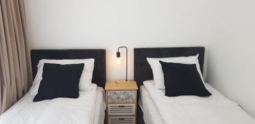 two beds with black and white pillows in a room at Apartamenty Cicha - bezpłatny parking in Krynica Zdrój