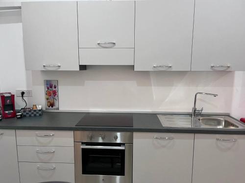 a kitchen with white cabinets and a stainless steel sink at Giannina House 22 in Cefalù
