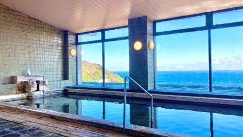 a house with a swimming pool with a view of the ocean at Itoen Hotel Atagawa in Higashiizu