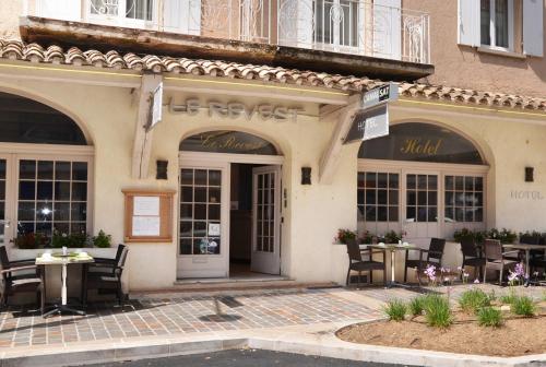 un restaurant avec des tables et des chaises en face d'un bâtiment dans l'établissement Hotel Le Revest, à Sainte-Maxime