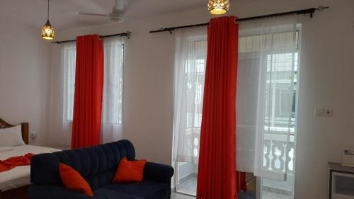 a bedroom with red curtains and a couch and a bed at Nestabs Homes in Mtwapa
