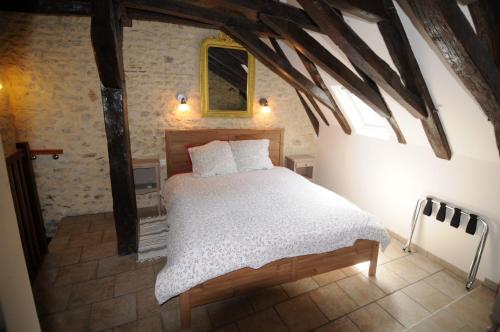 a bedroom with a bed in a room with beams at Le Passage in La Charité-sur-Loire