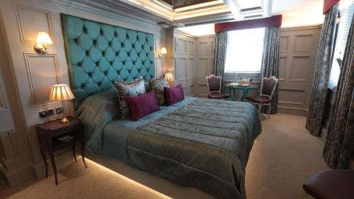 a bedroom with a large bed with a blue headboard at The Crown Hotel Bawtry-Doncaster in Doncaster