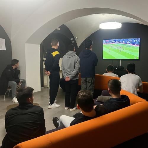 a group of people watching a soccer game on a television at Bohoostel in Bologna