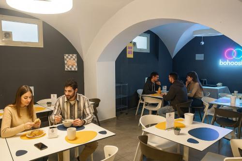 a group of people sitting at tables in a restaurant at Bohoostel in Bologna