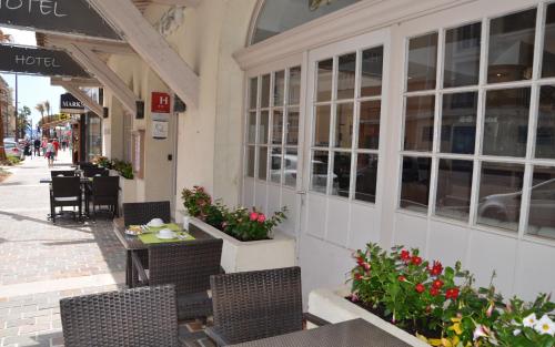 un restaurante con mesas, sillas y flores en la acera en Hotel Le Revest, en Sainte-Maxime