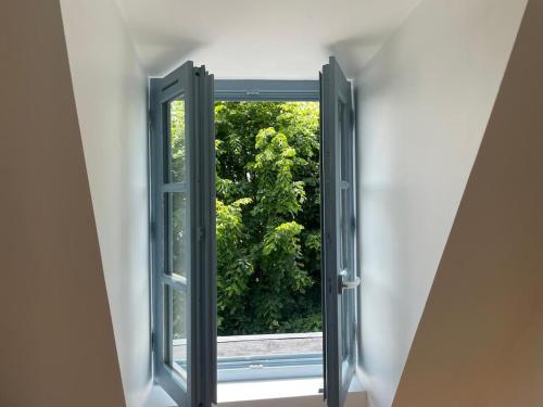 an open window looking out at a garden at Charmant appartement 2 chambres entièrement rénové avec parking au calme tout en étant à deux pas des commerces et restaurants in Orthez