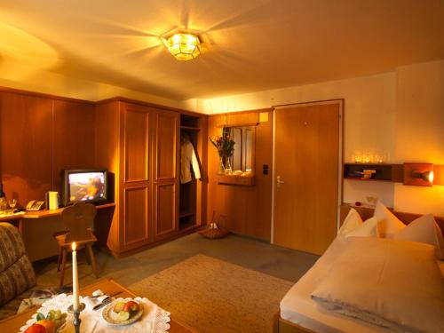 a bedroom with a bed and a tv and a table at Sporthotel Krone in Schoppernau