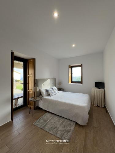 a white bedroom with a bed and a window at Casa da Trapa in Oliveira de Azemeis