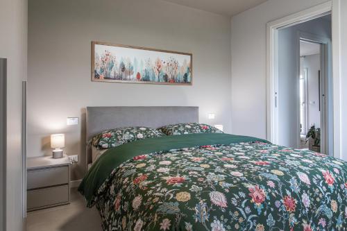a bedroom with a bed with a floral bedspread at Homy Apartments in Maniago