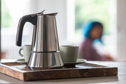 a tea kettle and two cups on a wooden tray at Homy Apartments in Maniago