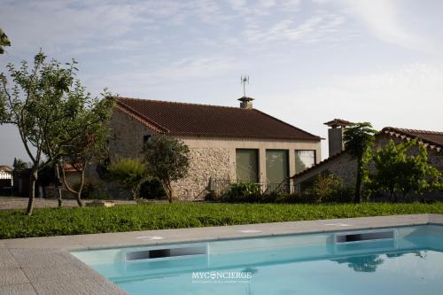 a villa with a swimming pool in front of a house at Casa da Trapa in Oliveira de Azemeis