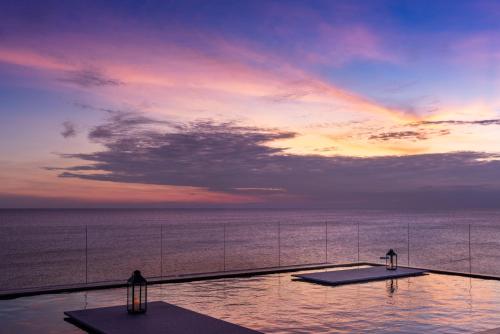 a swimming pool with a view of the ocean at sunset at Roy Hotel-Tianya Town Store in Sanya