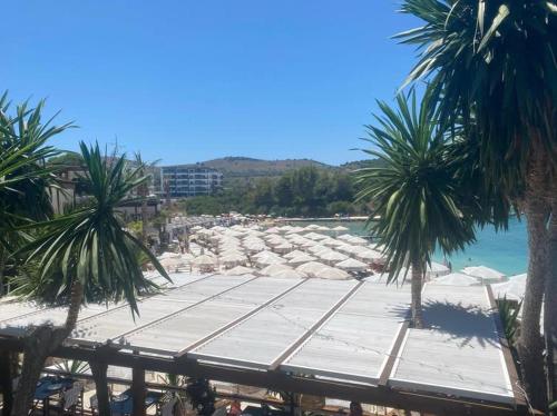 a sandy beach with palm trees and the ocean at HOTEL DENOEL in Ksamil