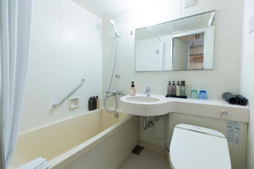 a bathroom with a sink and a toilet and a mirror at Hiyori Hotel Osaka Suminoekoen Station in Osaka