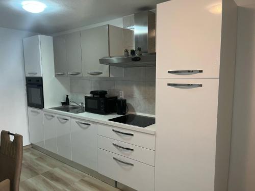 a kitchen with white cabinets and a black microwave at Apartman Marina Vrsi in Vrsi
