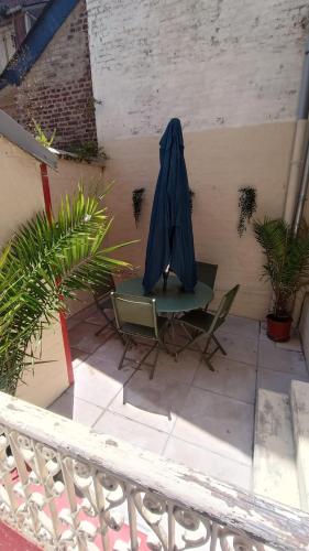 une terrasse avec une table, des chaises et un parasol dans l'établissement La Batelière, appartement mer avec patio privé, à Mers-les-Bains
