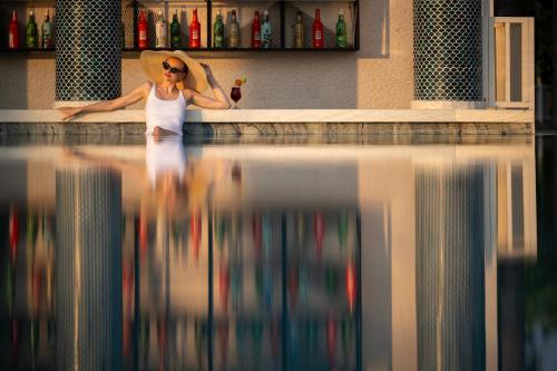 a woman wearing a hat standing next to a pool of water at Oz Hotels Incekum Beach in Alanya
