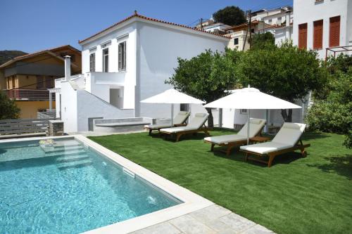 a yard with chairs and umbrellas and a swimming pool at Andros Neoclassical Villa NP1926 with Private Pool in Steniaí