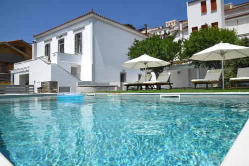 a swimming pool with chairs and umbrellas in front of a building at Andros Neoclassical Villa NP1926 with Private Pool in Steniaí