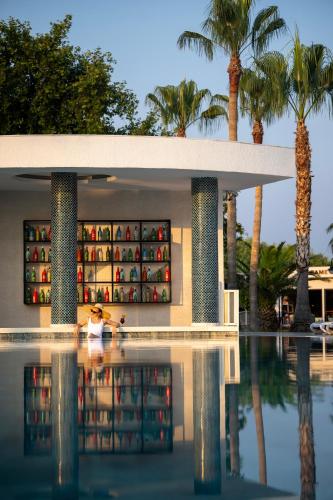 a person standing in a pool in front of a building with palm trees at Oz Hotels Incekum Beach in Alanya