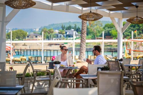 two people sitting at a table at an outdoor restaurant at Oz Hotels Incekum Beach in Alanya