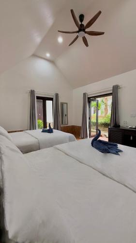 a row of four white beds with a ceiling fan at Nos Vetra Resort in Phú Quốc