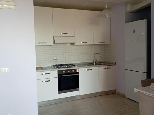 eine Küche mit weißen Schränken und einem Herd mit Backofen in der Unterkunft Arold Casa Vacanze in Francavilla al Mare