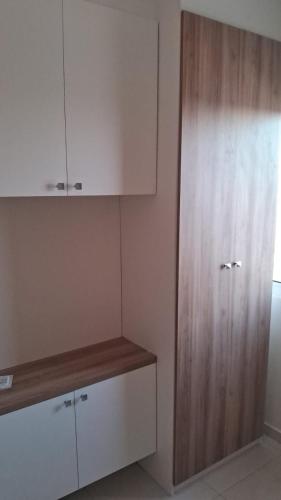 a kitchen with white cabinets and a wooden cabinet at Apto Aconchegante no coracao da Ilhotas in Teresina