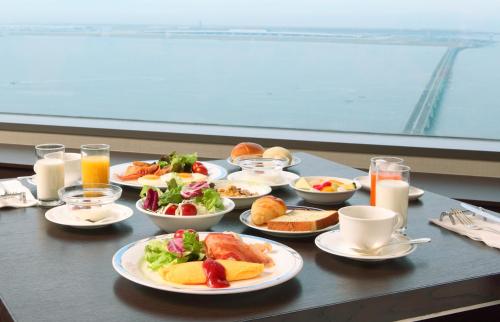 a table with plates of food and cups of orange juice at Star Gate Hotel Kansai Airport in Izumi-Sano