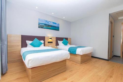 a bedroom with two beds with blue pillows at GreenTree Inn Nanjing Confucius Temple Sanshan Street Subway Station Express Hotel in Nanjing