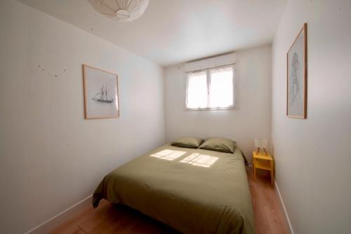 Un dormitorio con una cama en una habitación con ventana. en Maison avec jardin arboré et calme, en Jard-sur-Mer