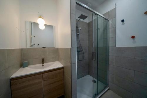 Un baño con ducha de cristal y lavabo. en Maison avec jardin arboré et calme, en Jard-sur-Mer