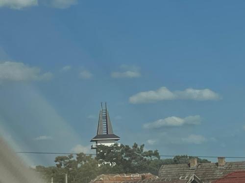 a church steeple in the sky over roofs at Anett Wellis Apartman Poroszló in Pusztavacs
