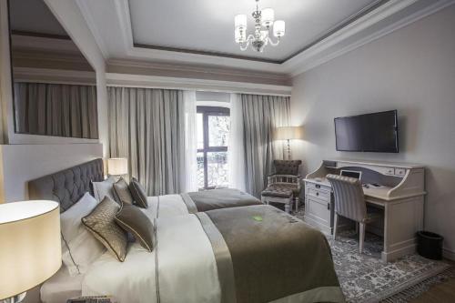 a bedroom with a bed and a desk and a television at Boutique 19 Hotel in Baku