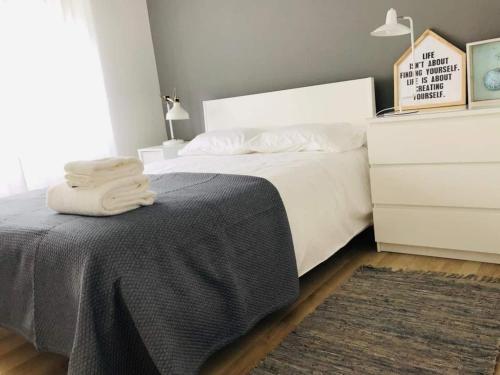 a bedroom with a bed and a dresser with towels on it at Spacious 3 Bedroom Apartment 20 Min To Lisbon in Montijo