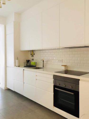 a kitchen with white cabinets and a black oven at Spacious 3 Bedroom Apartment 20 Min To Lisbon in Montijo