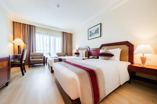 a hotel room with two beds and a chair at Pearl River Hotel in Hai Phong