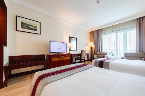 a hotel room with two beds and a desk at Pearl River Hotel in Hai Phong
