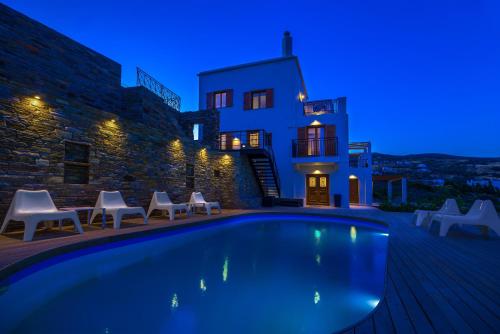 a villa with a swimming pool at night at Belvedere Andros in Batsi