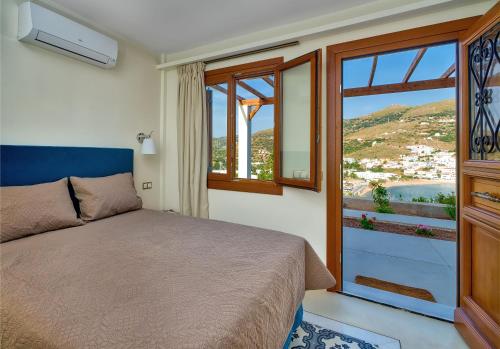 a bedroom with a bed and a large window at Belvedere Andros in Batsi