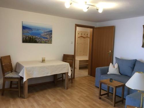 a living room with a table and a blue couch at Ferienwohnungen Familie Brunner, Kreuth-Reitrain in Oberach