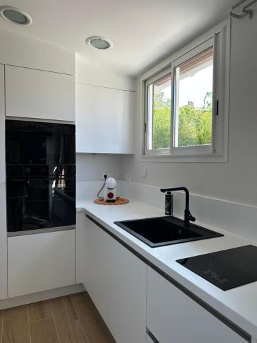 une cuisine blanche avec un évier et une fenêtre dans l'établissement Appartement T1 centre ville sanary, plage à pied, quartier Portissol, à Sanary-sur-Mer