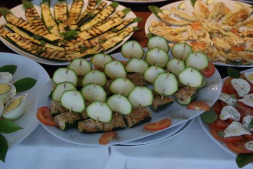 a table topped with plates of food with tomatoes and potatoes at Residence Aprilia in Grado