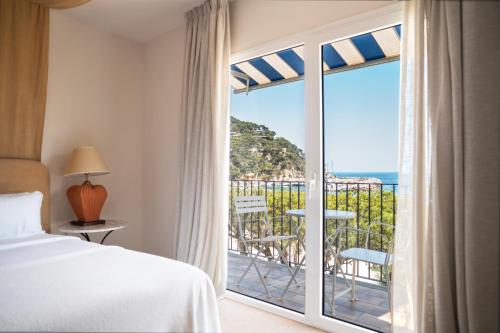 una camera d'albergo con un letto e una grande finestra di Hotel Isabella's Llafranc a Llafranc