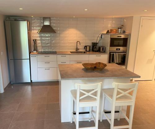 a kitchen with a counter and two stools in it at Plomben C in Båstad