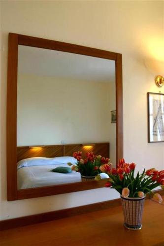a mirror in a bedroom with a bed and flowers at Hotel Villa Pina Antico Francischiello in Massa Lubrense