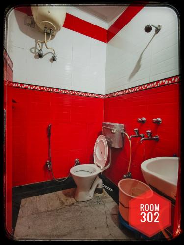 a red bathroom with a toilet and a sink at Shri Ganga View Guest House in Rishīkesh